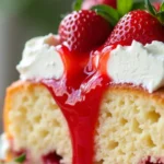 Close-up of strawberry poke cake with whipped topping and fresh strawberries
