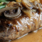 Close-up of Salisbury steak topped with mushroom gravy, showcasing its juicy texture and rich brown sauce.