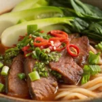 Beef noodle soup with tender beef slices, hand-pulled noodles, bok choy, and spicy broth
