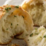 Freshly baked garlic knots torn open to reveal a soft, fluffy interior, topped with chopped parsley and melted garlic butter.
