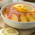 Peach Lemonade Jello with sliced peaches and lemons in a white bowl