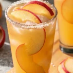 Peach Ring Cocktail with peach slices and sugar rim in a tall glass