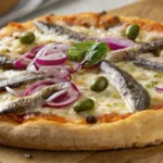 Close-up of a sardine pizza topped with green olives, red onions, and fresh basil on a golden crust.